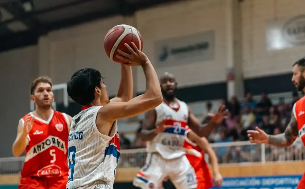 Un ballon de basket qui passe dans le panier dans une salle illuminée, mettant en valeur la précision du tir et les points marqués lors d'un match professionnel.