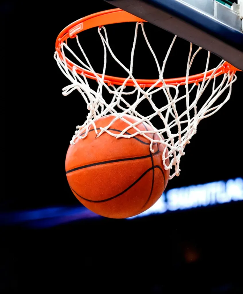 Un basketteur effectuant un dunk puissant en plein vol dans un stade, illustrant l'athlétisme et l'intensité du jeu.